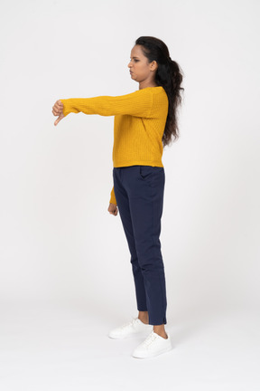 Vista lateral de uma garota com roupas casuais mostrando o polegar para baixo
