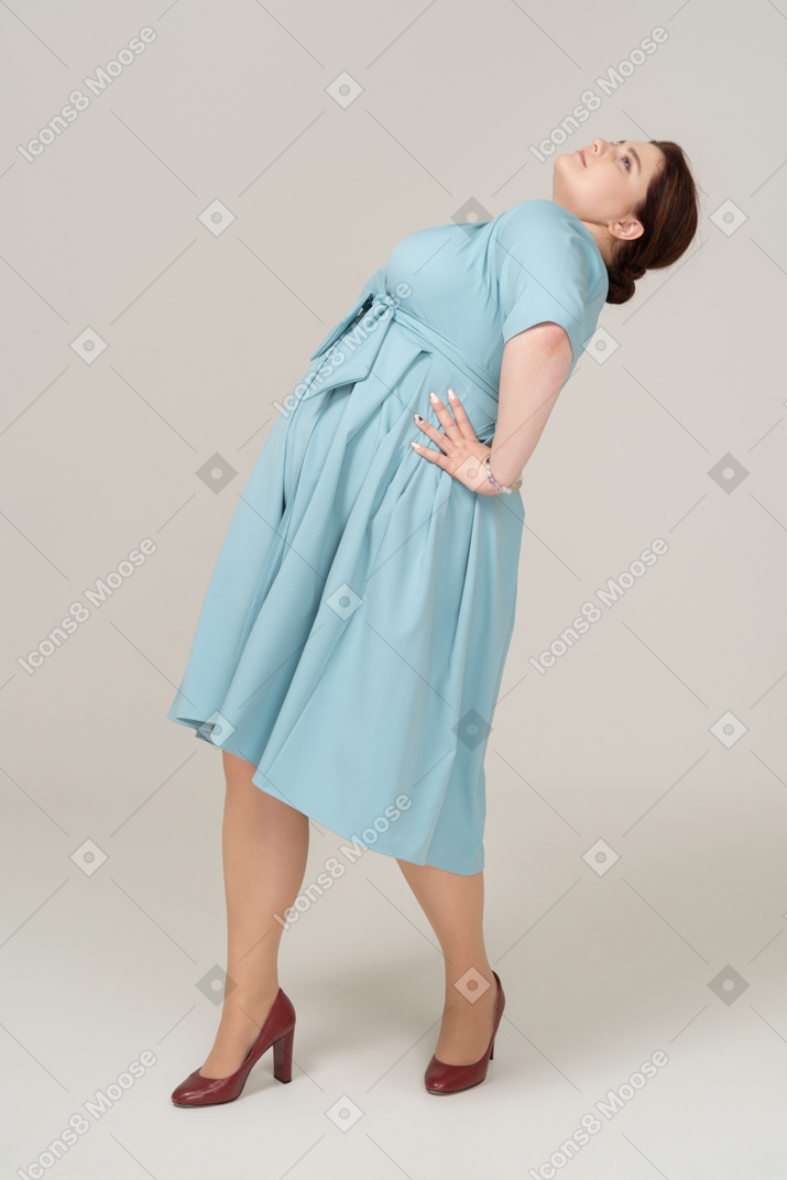 Вид сбоку женщины в синем платье, откинувшись назад