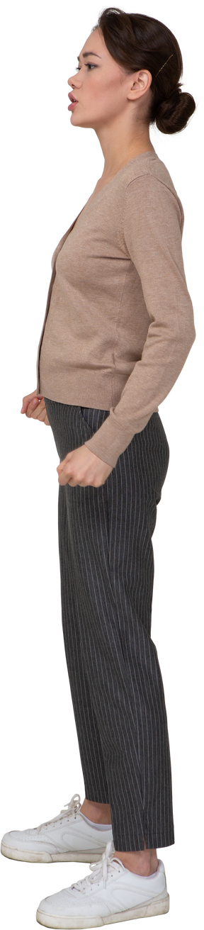 Side view of a young lady in beige pullover clenching fists