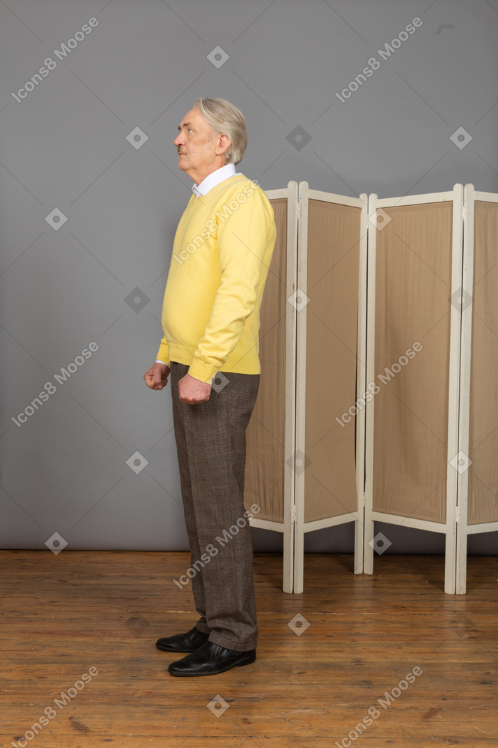 Side view of a nervous old man looking up and clenching fists
