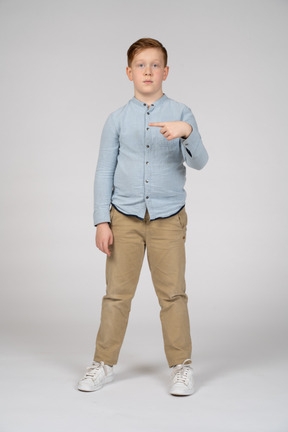 Vista frontal de um menino apontando com o dedo e olhando para a câmera