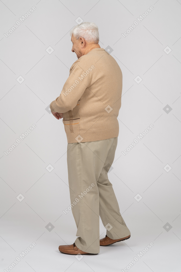 Side view of an old man in casual clothes walking
