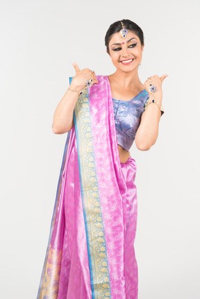 Young indian woman in purple sari showing thumbs up