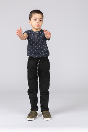 Vista frontal de um lindo garoto em roupas casuais batendo palmas