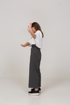 Side view of an unwilling young lady in office clothing outstretching arm