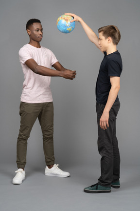 Two young men playing volleyball using the earth mini globe