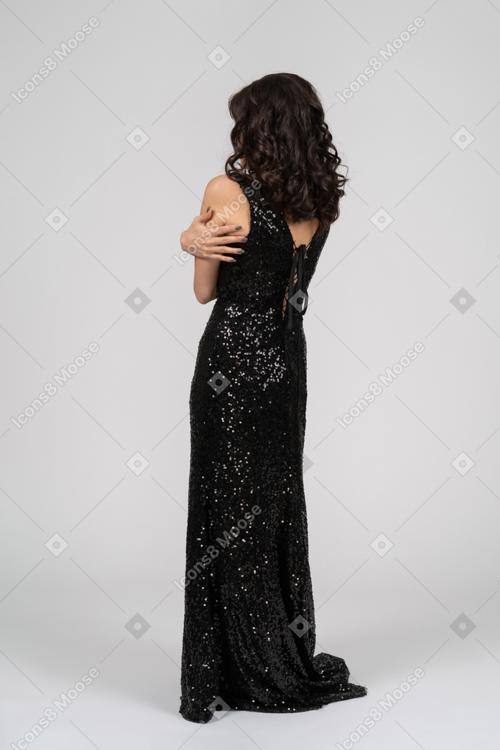 Mujer en vestido de noche negro abrazándose a sí misma