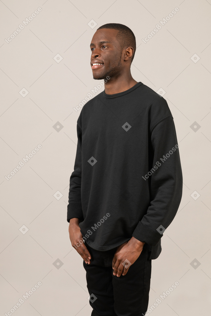 Jeune homme souriant debout avec ses mains dans les poches
