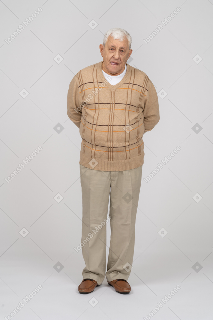 Vista frontal de un anciano con ropa informal de pie con las manos detrás de la espalda