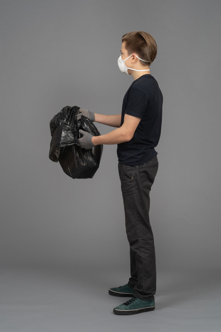 A man holding a black trash bag sideways to camera