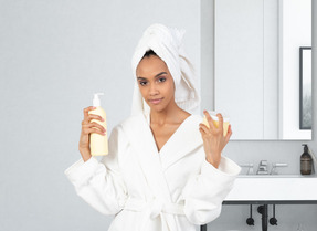 A woman in a bathrobe holding skin care products