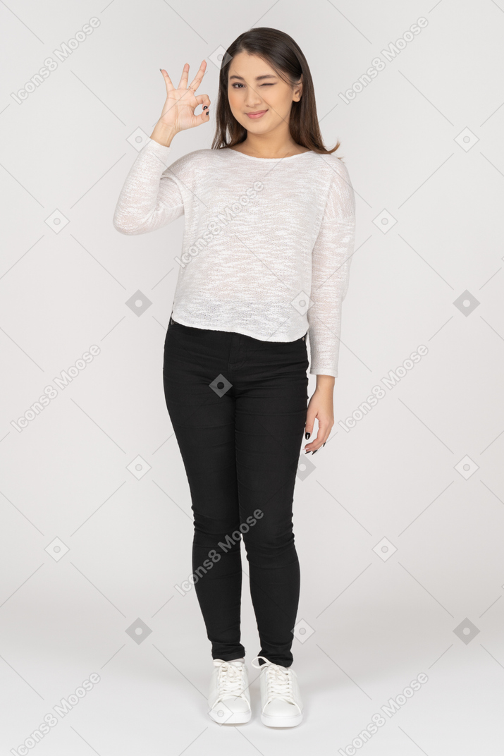 Front view of a young indian female in casual clothing showing ok gesture
