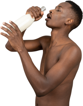 A shirtless young man drinking milk