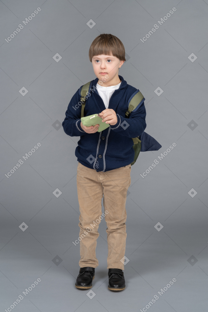 Little boy with a backpack holding a pencil case