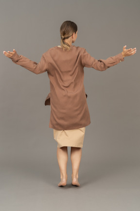 Back view of a young woman with arms wide open