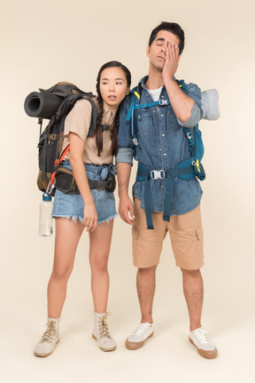 Giovane coppia interrazziale di escursionisti dall'aspetto stanco
