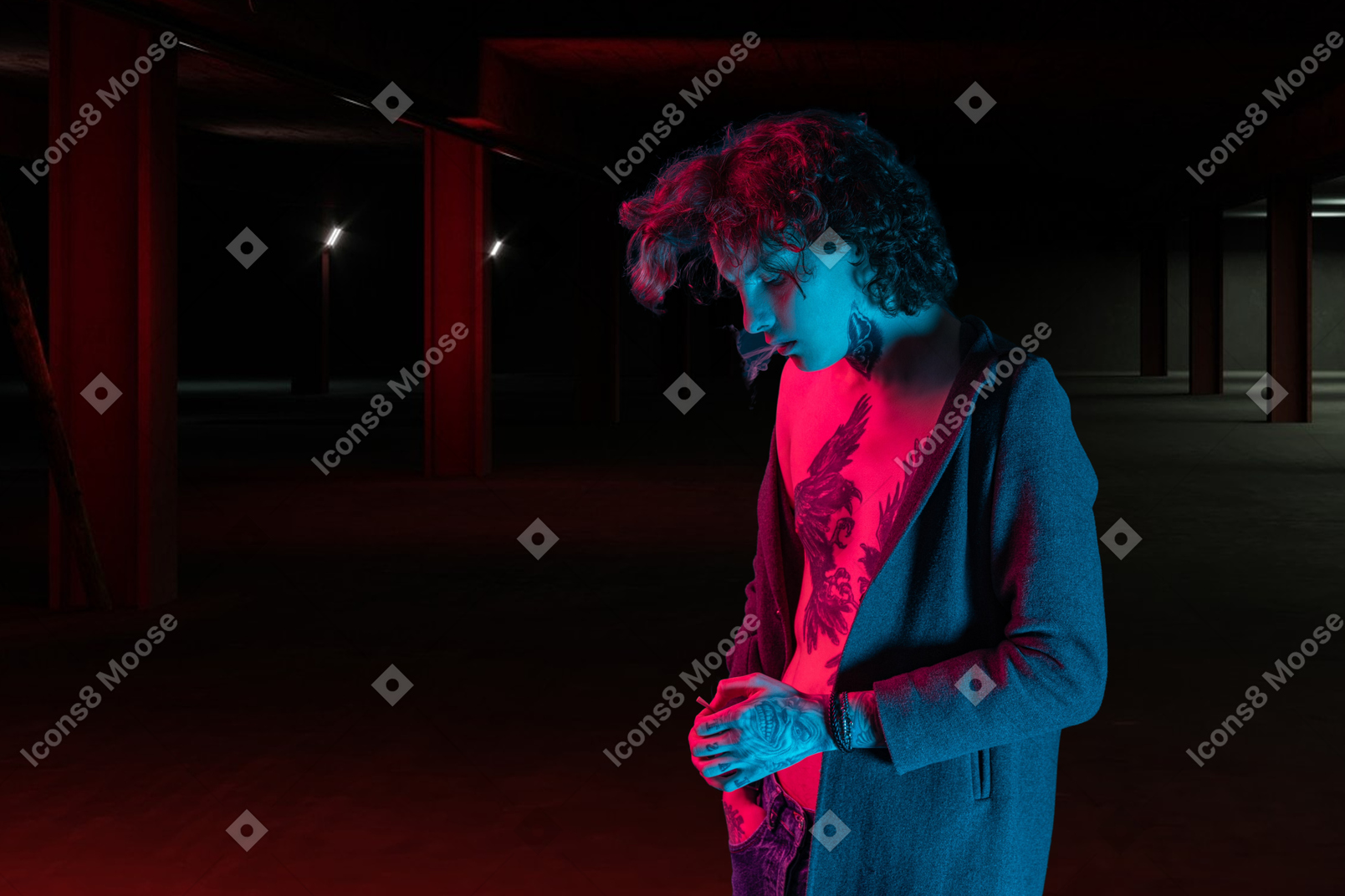 A young man standing in a dark parking garage and smoking