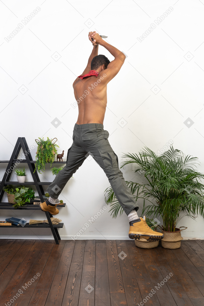 Strong man holding a knife with both hands jumping up