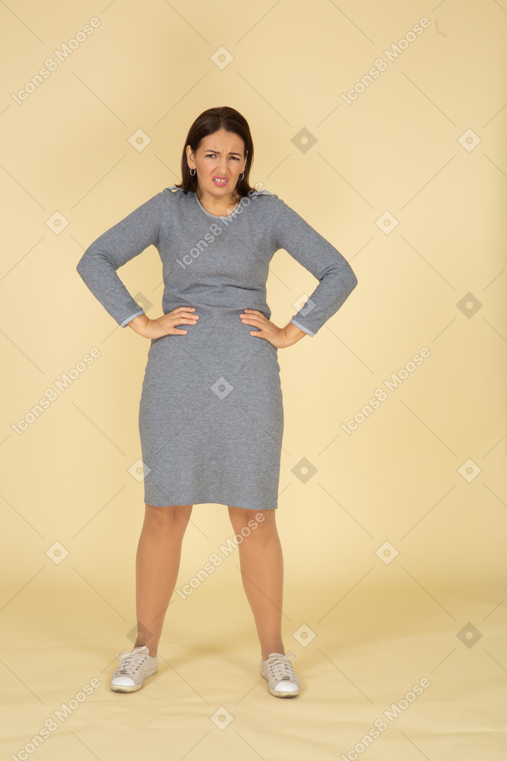 Front view of a woman in grey dress standing with hands on hips