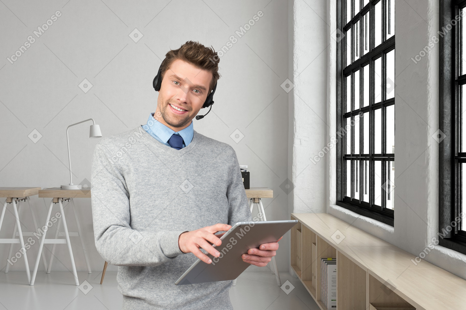A man wearing a headset and holding a tablet in an office