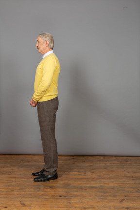 Side view of a depressed old man wearing a yellow pullover and looking aside