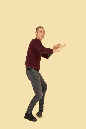 Front view of a young man in red pullover outstretching his hands