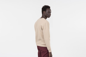 A young black man in a grey sweater standing alone on the white background