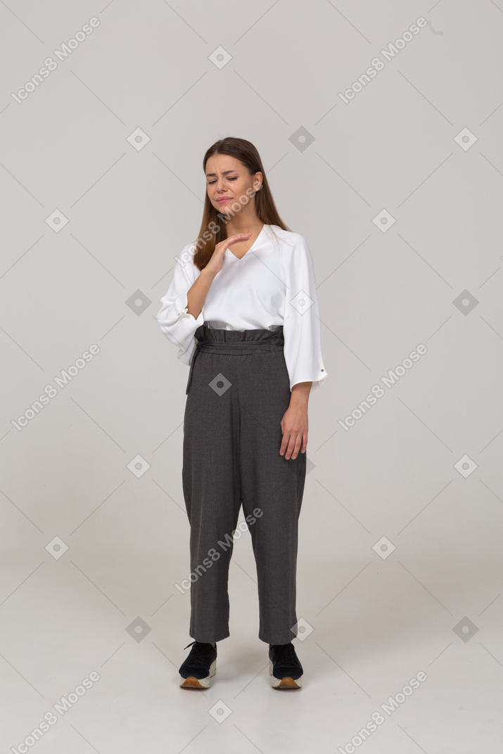 Front view of an unwilling young lady in office clothing raising hand