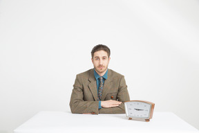 Handsome young man sitting near the clock with his hands folded