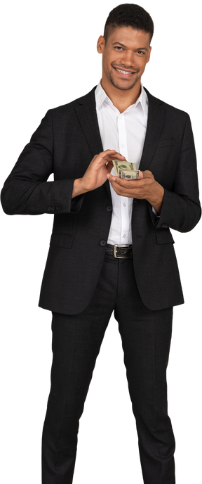 Vista frontal de um jovem de terno preto desperdiçando dinheiro