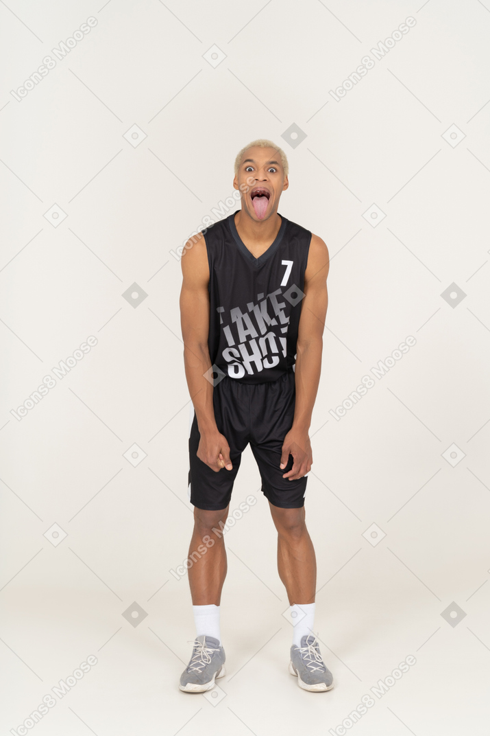 Vista frontale di un giovane giocatore di basket maschio pazzo che mostra la lingua