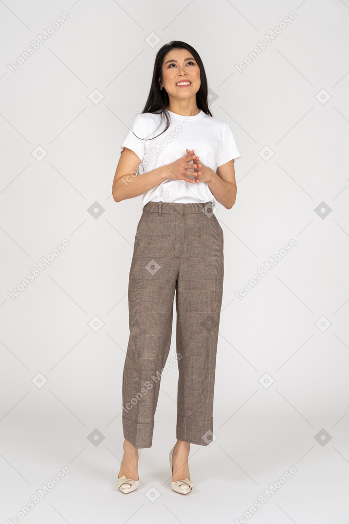 Front view of a pleased young lady in breeches and t-shirt holding hands together