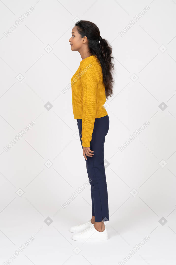 プロフィールに立っているカジュアルな服を着て幸せな若い女性