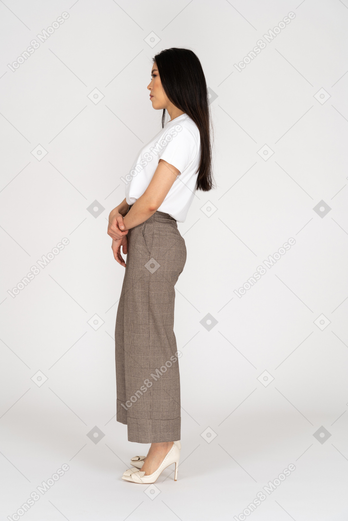 Side view of a young lady in breeches and t-shirt standing still