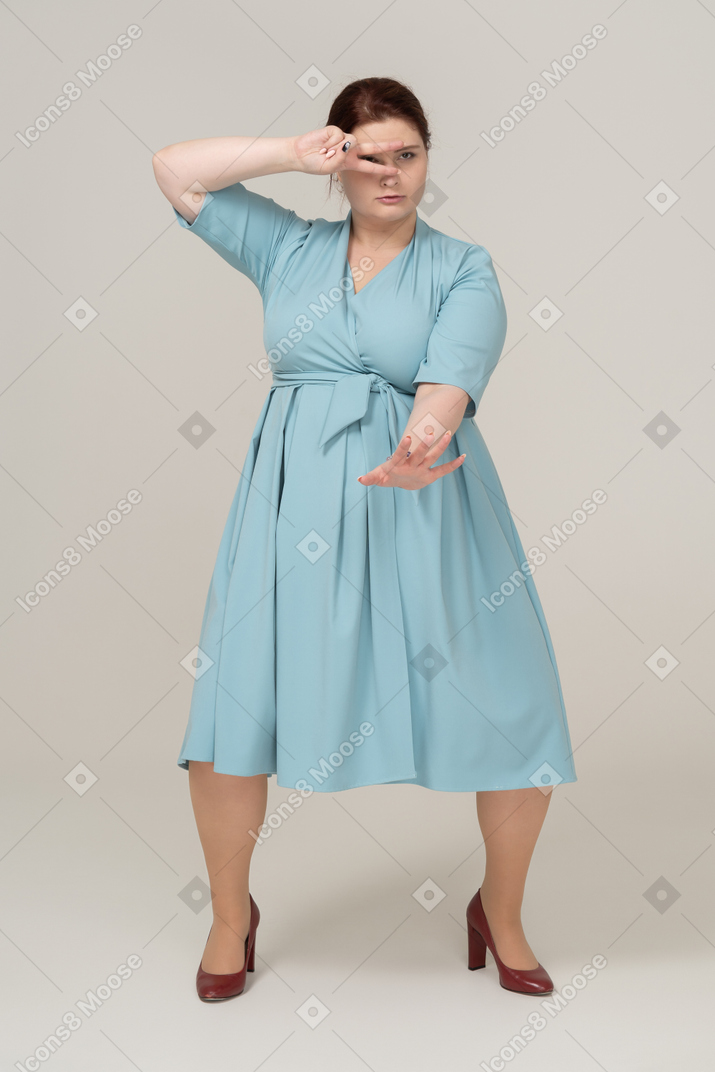 Vista frontal de uma mulher de vestido azul mostrando sinais de v