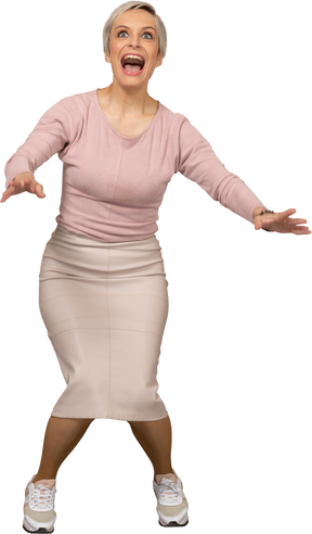Front view of a happy woman in casual clothes squatting and outstretching arms