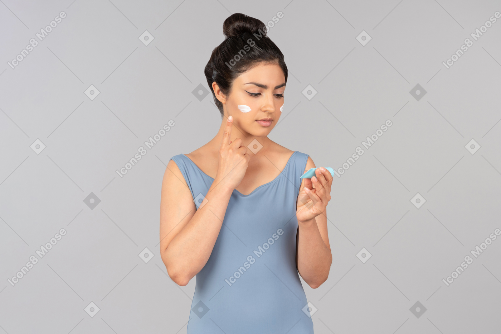 Young indian woman in blue tank top applying face cream
