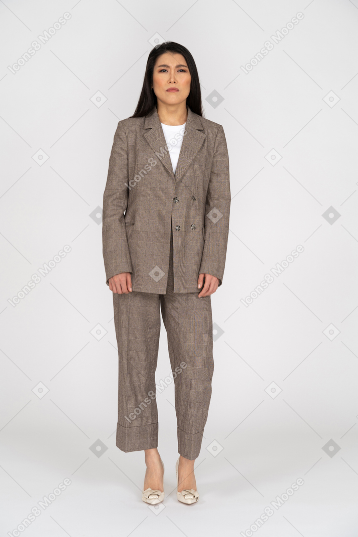 Front view of a suspicious young lady in brown business suit