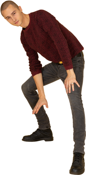 Front view of a young man in red pullover making a lunge