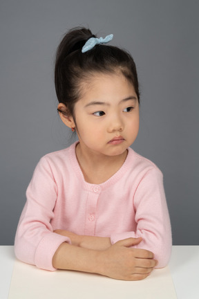 Menina séria sentado ainda na mesa dela