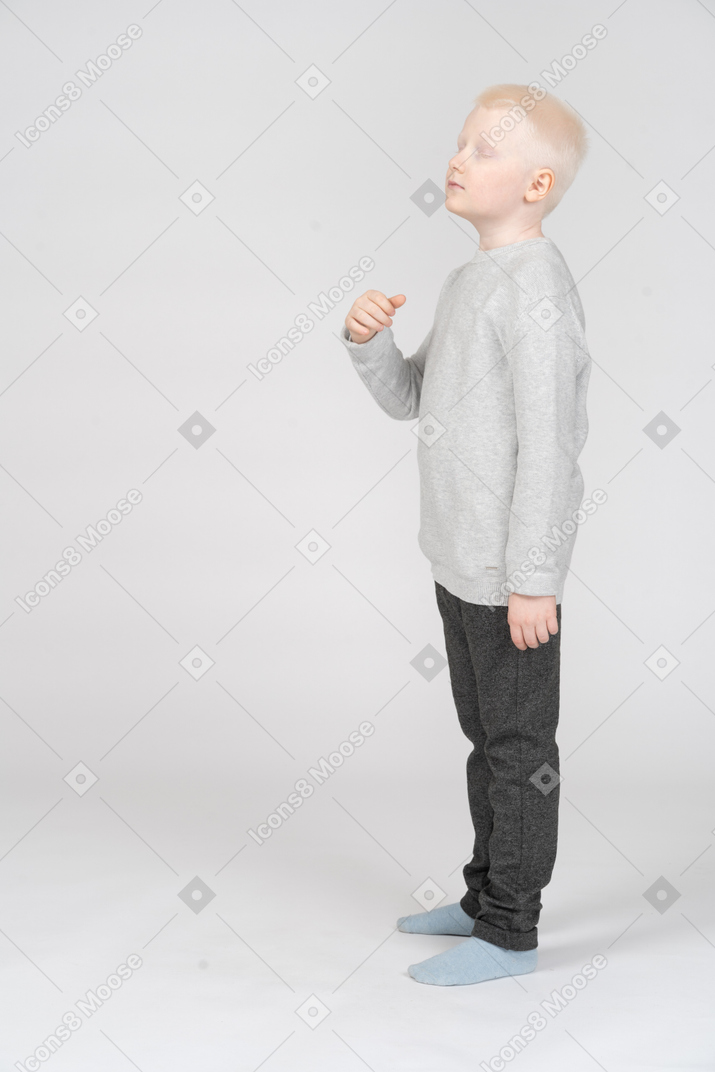 Side view of a boy standing with his eyes closed