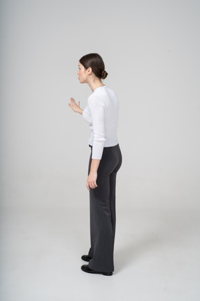 Vista lateral de uma mulher de calça preta e blusa branca gesticulando