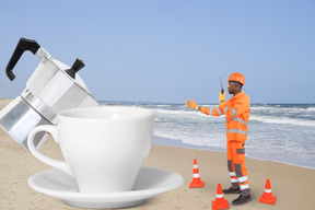A man standing on a beach next to a cup of coffee