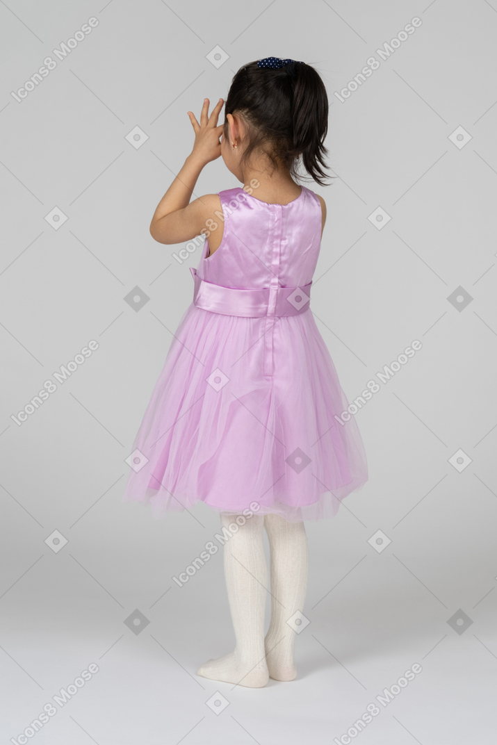 穿着粉红色连衣裙的女孩透过手臂看