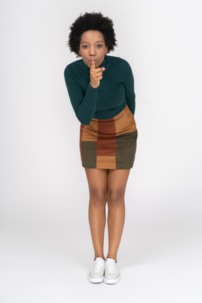 Young girl making a hush gesture and bending over