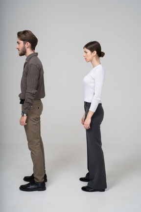 Side view of a young couple in office clothing standing still
