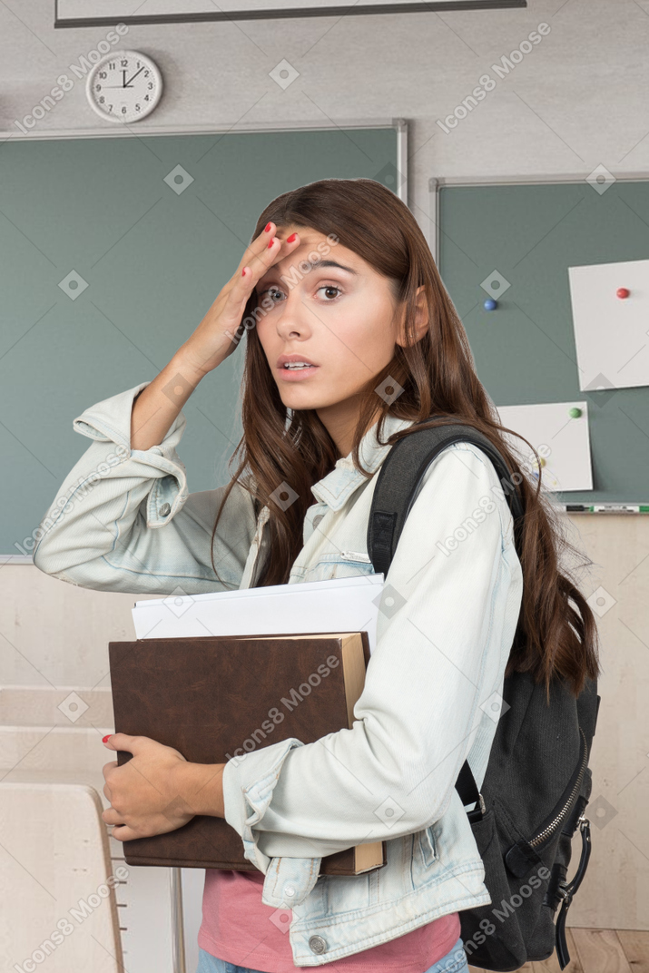 Confused female student with books