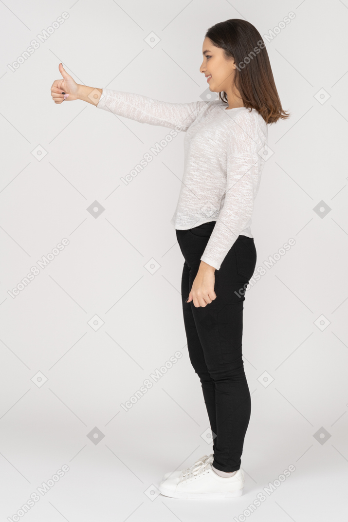Vue latérale d'une jeune femme indienne dans des vêtements décontractés montrant le pouce vers le haut