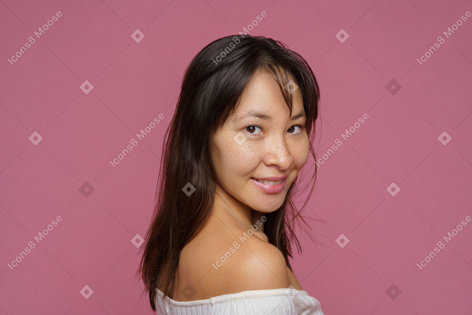 Three-quarter back view of a smiling young female looking at camera