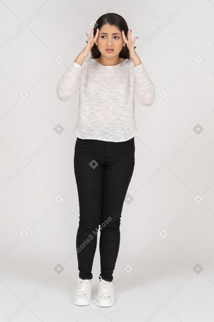 Front view of a shocked young indian female in casual clothes touching head